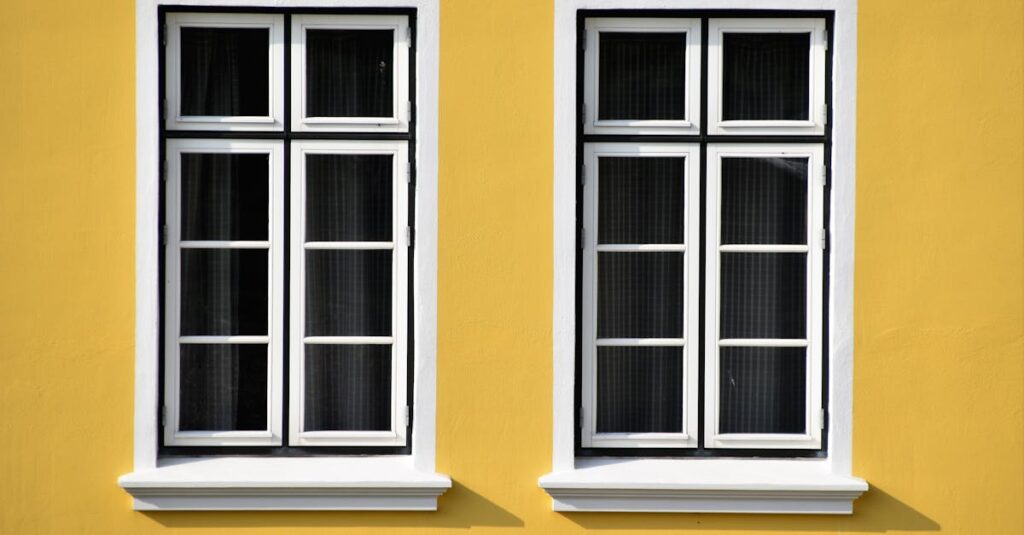 Two white-framed windows on a vibrant yellow building facade in Büsum, Germany.