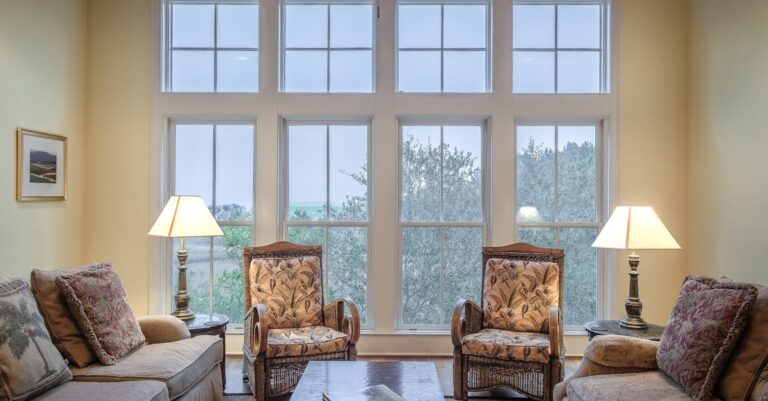 A cozy living room showcasing elegant furniture with large glass windows and warm lighting.